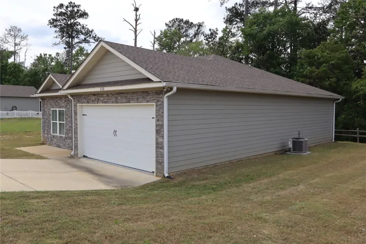 This house features a stone facade and siding, with an attached garage and a spacious driveway.