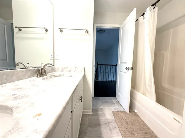 This bright bathroom features a spacious vanity with elegant countertops and a convenient shower.