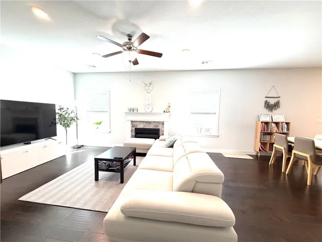 Bright and airy living room with dark wood flooring and a cozy fireplace, ideal frelax
