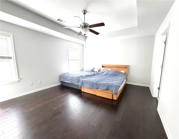 This spacious bedroom features elegant wood flooring and an appealing tray ceiling.