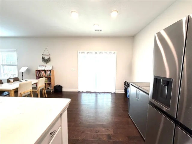 This welcoming space features rich wood flooring, connecting a bright dining area with a modern kitchen.