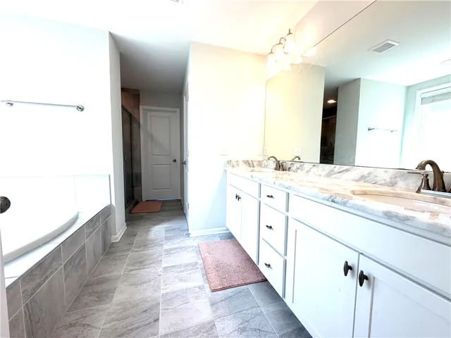 This spacious bathroom offers a double vanity and a luxurious soaking tub for ultimate relaxation.