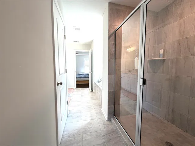 This spacious bathroom offers elegant tile flooring and a luxurious glass-enclosed shower.