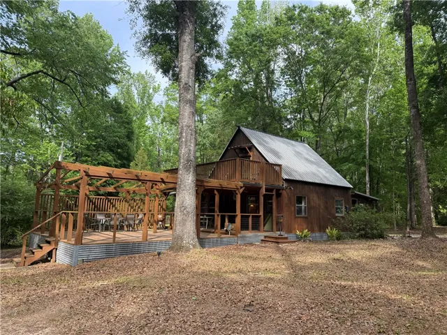 This charming home features a wooden exterior and a spacious deck, perfect for outdoor living.