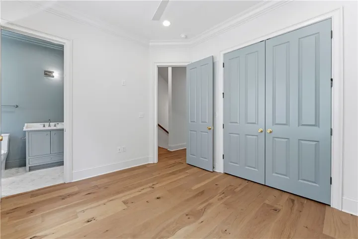 This inviting bedroom features rich hardwood flooring and convenient access to a modern bathroom.
