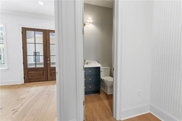 This powder room features elegant fixtures and rich hardwood flooring, with glass panel French doors leading to an adjacent area.