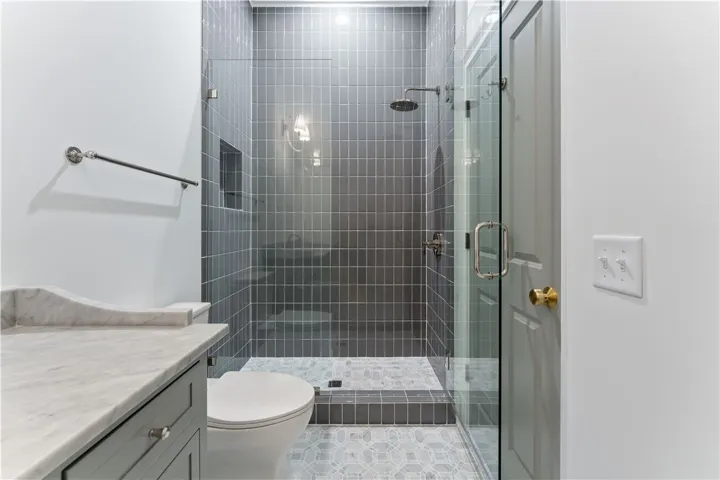 This modern bathroom features a tiled shower and an elegant marble vanity.