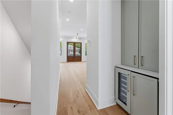 This bright hallway showcases rich hardwood flooring and leads to a welcoming living space.