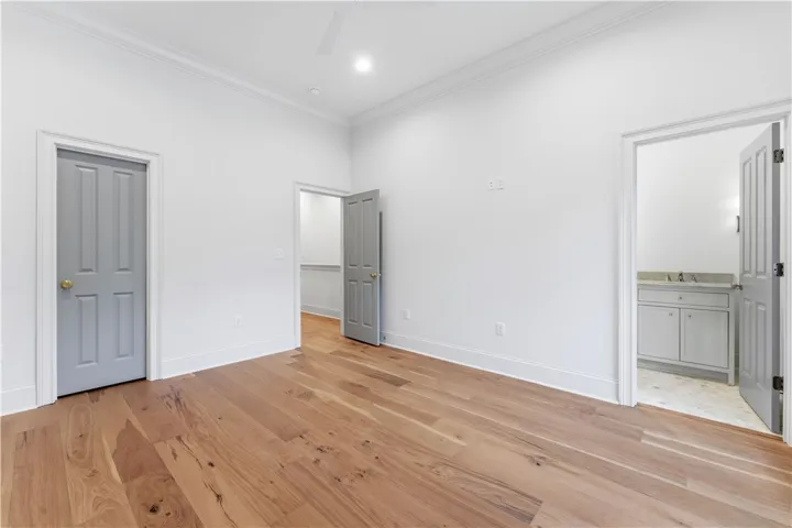 This airy bedroom features bright walls and polished wood flooring.