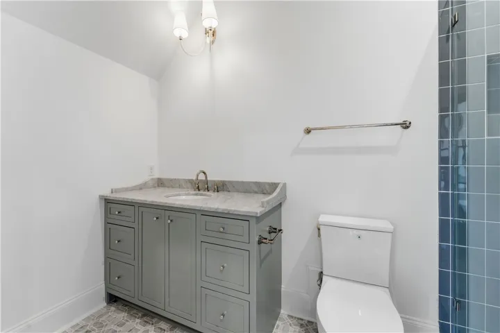 This bathroom features a contemporary vanity with a marble counter, sleek fixtures, and stylish tile flooring.