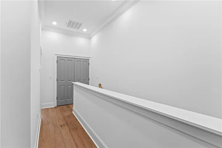 This bright hallway features beautiful hardwood flooring and ample recessed lighting.