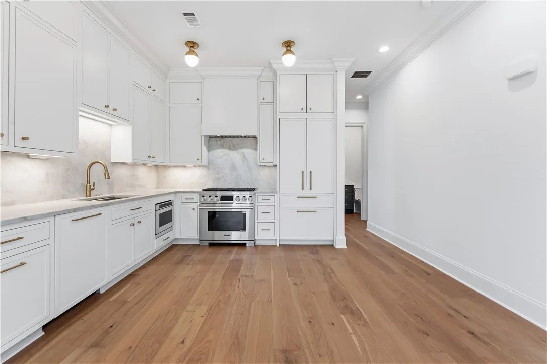 This modern kitchen features pristine cabinetry, sleek appliances, and elegant hardwood flooring.