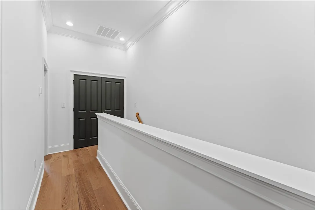 This bright hallway features beautiful hardwood flooring and elegant crown molding.