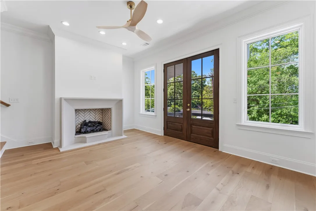 This bright space features a fireplace, hardwood floors, and French doors leading to outdoor serenity.