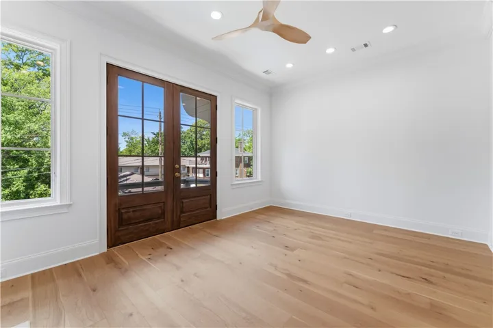 This bright space features natural light, elegant wood floors, and a modern ceiling fan.