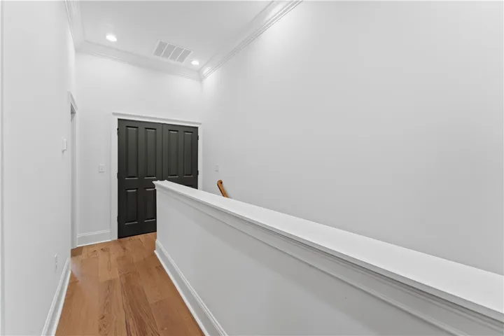This bright hallway features beautiful hardwood flooring and elegant crown molding.