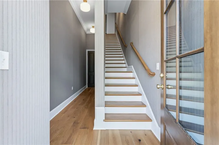 This inviting entry features rich wood floors, a stylish staircase, and a striking glass panel door.