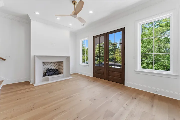 This bright space features a fireplace, hardwood floors, and French doors leading to outdoor serenity.