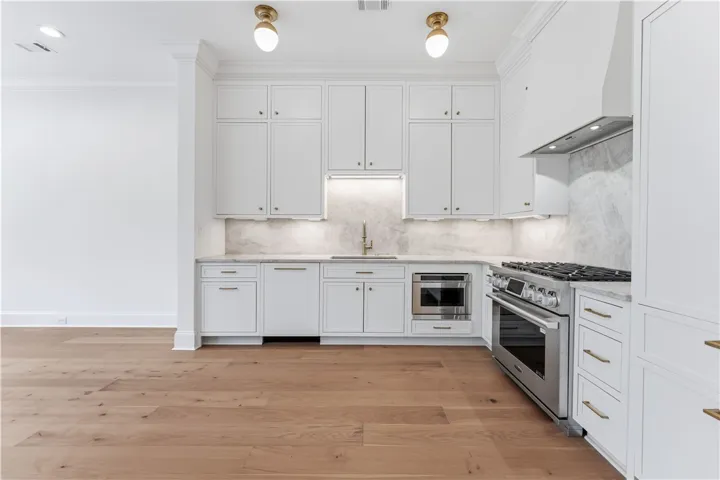 This sleek kitchen features white cabinetry, modern appliances, and beautiful hardwood flooring.