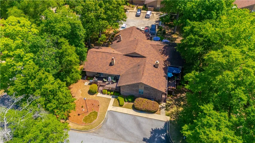 An aerial view showcases a residential building nestled amongst lush trees, featuring a spacious deck.