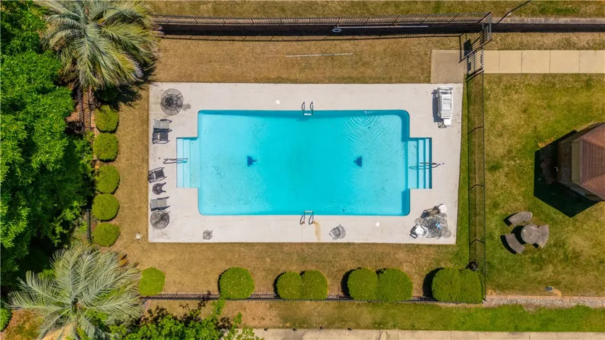An aerial view showcases a sparkling pool nestled amidst lush greenery and ample outdoor space.