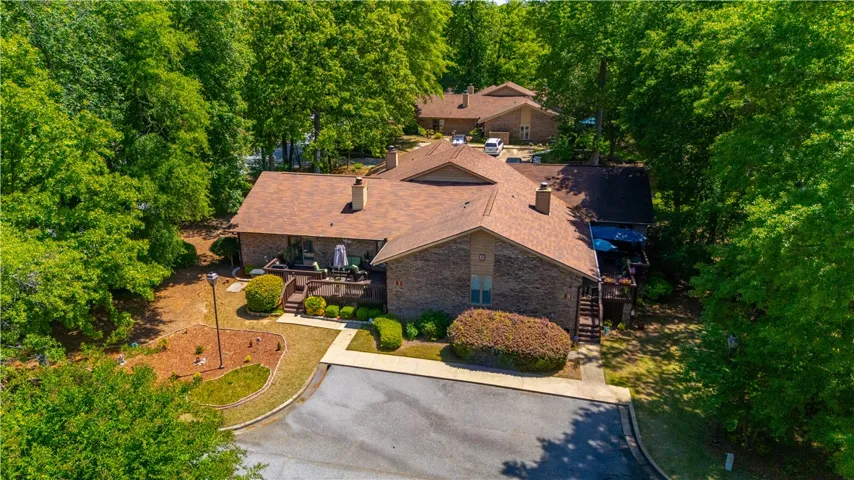 This charming residence is nestled among mature trees, featuring a spacious deck for outdoor living.