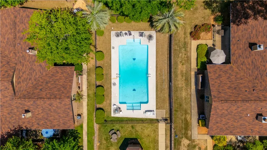 An aerial view showcases a vibrant pool nestled between residences, offering a refreshing retreat.