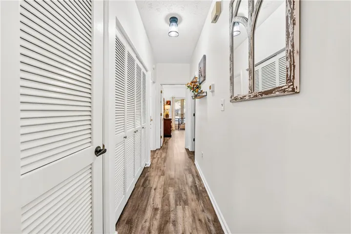This inviting hallway features durable wood flooring and functional louvered doors, offering both style and utility.