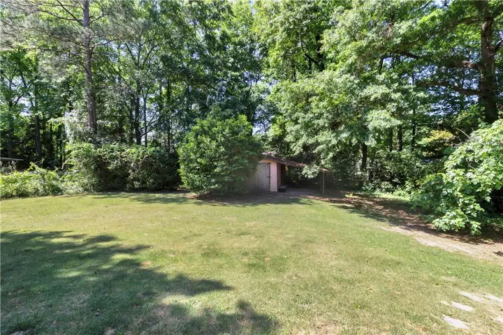 This verdant outdoor space features mature trees and a charming storage shed.