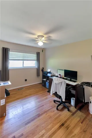 This versatile room features warm hardwood floors and a ceiling fan, perfect for a comfortable home office.