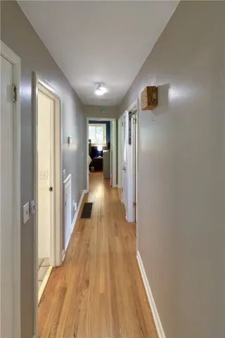 This spacious hallway features polished hardwood floors, guiding you to inviting rooms ahead.
