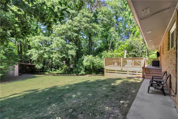 This verdant backyard features a spacious wooden deck and ample green space for outdoor activities.