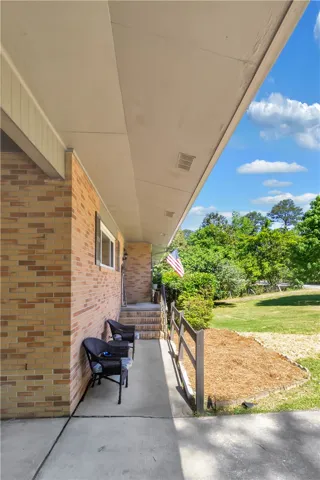 This inviting porch offers a tranquil retreat overlooking a lush, verdant yard.