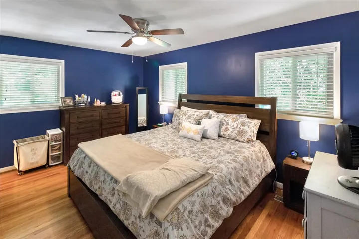 This spacious primary bedroom features rich hardwood floors and abundant natural light through multiple windows.