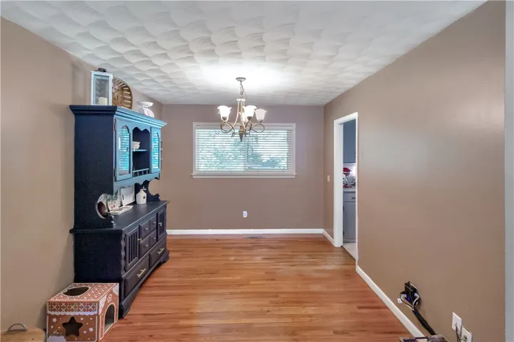 This inviting dining area features warm hardwood floors and a charming chandelier, perfect for intimate gatherings.