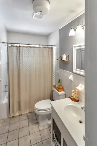 This bright bathroom features sleek tile flooring, a functional vanity, and a refreshing shower.