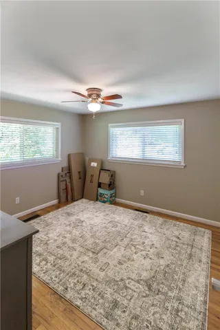 This spacious bedroom offers abundant natural light and warm hardwood flooring.