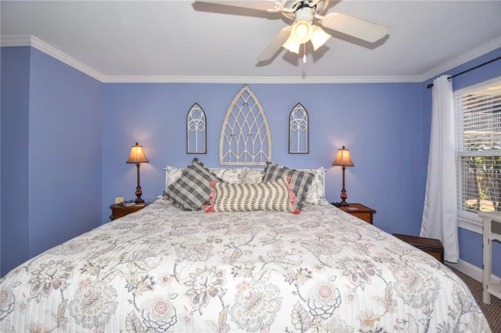 This cozy bedroom features crown molding and a ceiling fan, creating a comfortable and inviting atmosphere.