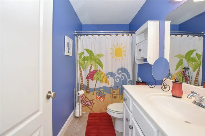 This bathroom features a single vanity, a toilet, and tiled flooring.