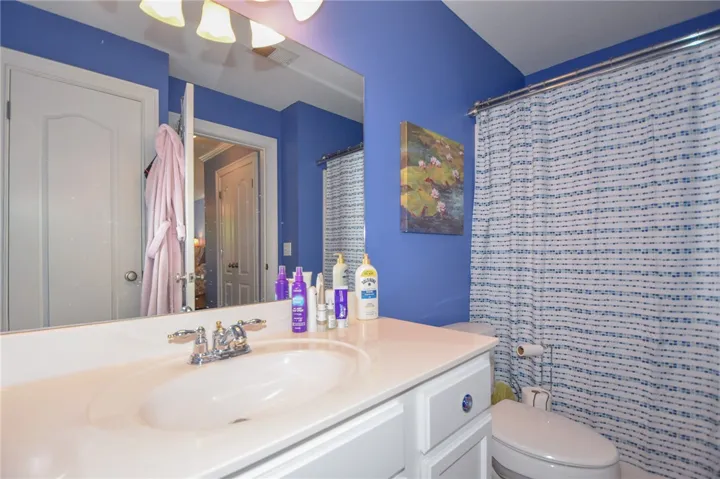 A well-lit bathroom featuring a vanity with a mirror and a clean toilet area.