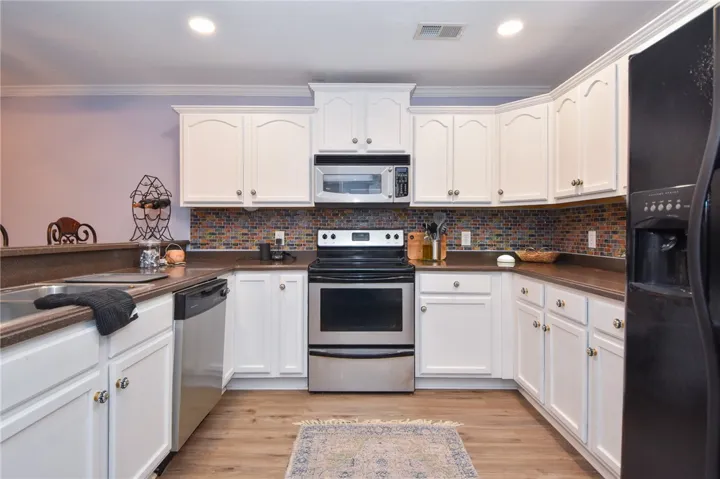 This modern kitchen features crisp white cabinetry and essential appliances for daily living.