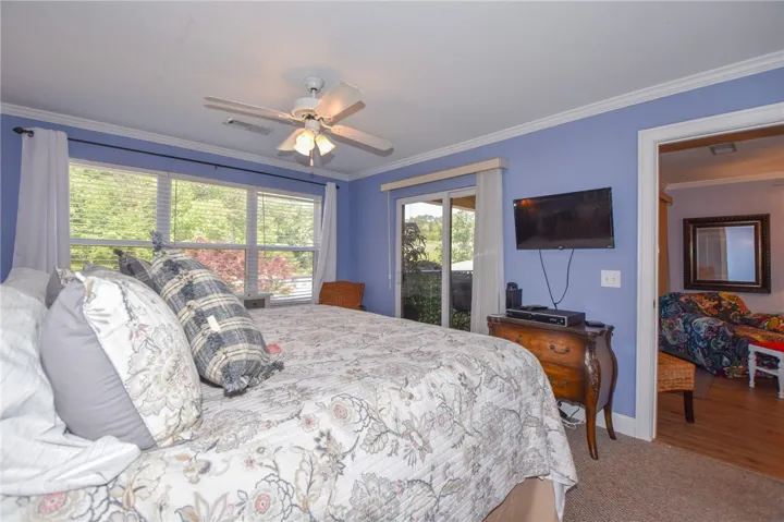 This cozy bedroom offers serene views through expansive windows and direct access to outdoor living.
