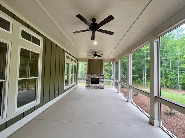 This screened porch offers serene wooded views and a cozy fireplace, perfect for outdoor relaxation.