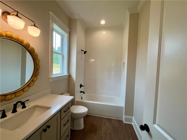 This secondary bathroom features a sleek vanity, elegant mirror, and a classic bathtub with tiled walls.