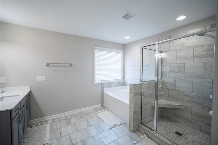 This bathroom features a sleek vanity, a spacious soaking tub, and a modern walk-in shower.