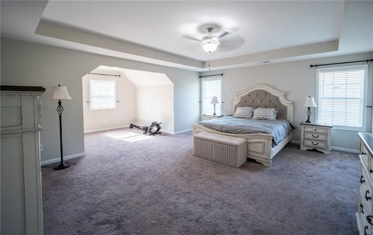 This expansive primary bedroom offers a comfortable and inviting retreat with architectural ceiling details.