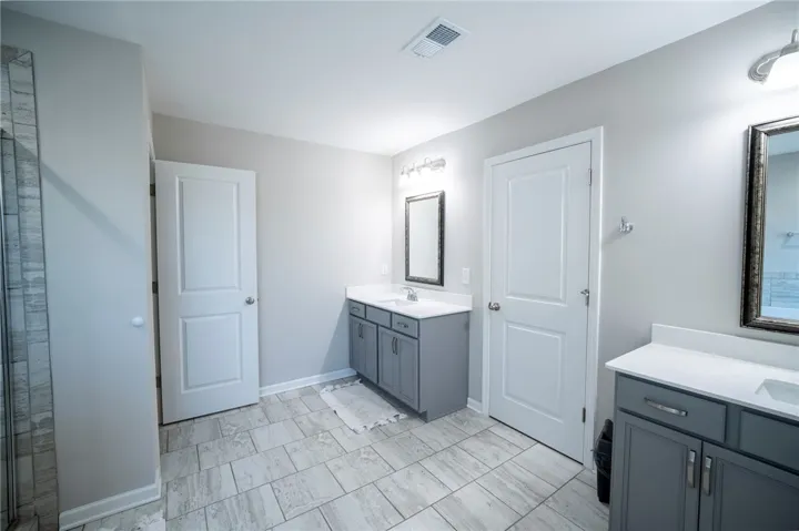 This spacious bathroom offers dual vanities and modern tile flooring for a refreshing ambiance.