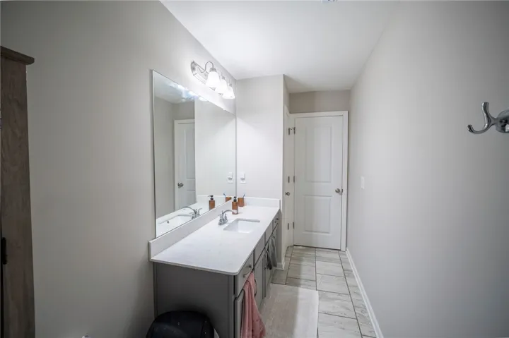 This clean bathroom features a modern vanity, a large mirror, and durable tile flooring.