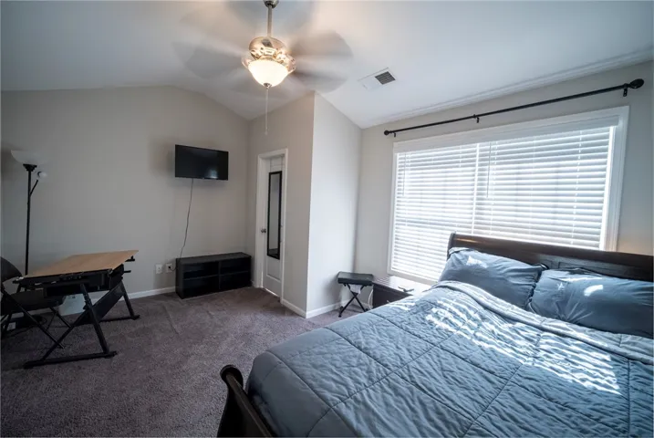 This cozy bedroom features comfortable carpeting and a vaulted ceiling, creating an inviting retreat.
