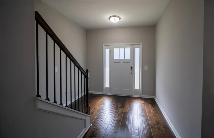 This inviting entryway showcases a hardwood floor and a staircase leading to the upper level.
